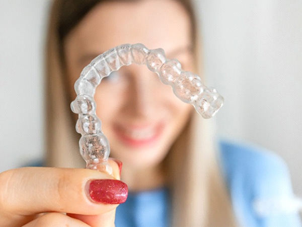 Close-up of clear orthodontic retainer, held in woman’s hand